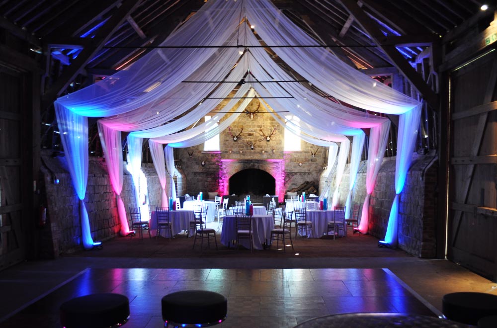 Wick bottom barn with ceiling coverage drop wall drapes with Red and Blue uplighting for a wedding party