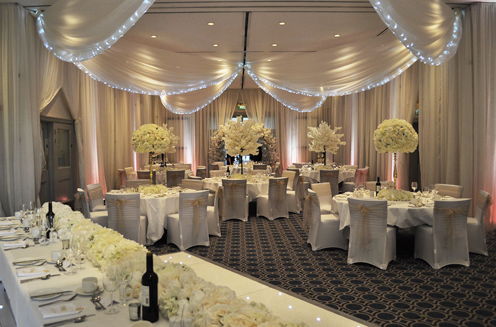 Bowood Hotel, Spa and Gold resport wedding with wall and ceiling drapery with LED fairy lights and pink and white uplighters.