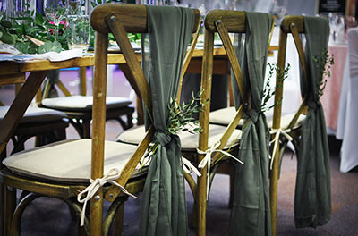 Moss chiffon chair drops, with foliage, on dark cross-back chairs