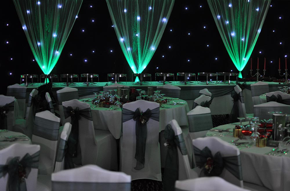 Green uplighters and black starcloth backdrop behind top table for a wedding
