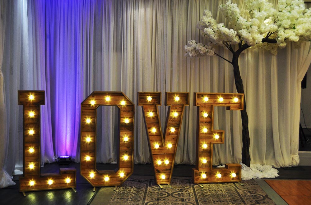 Life Sized Wooden Rustoc LOVE letters with warm white fairground style LED bulbs for a wedding with a blossom tree at Tortworth Court