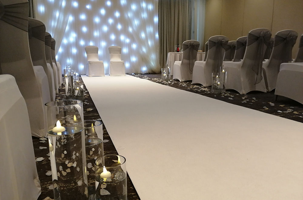 Starlit backdrop with white aisle runner with flaoting candles for a wedding in Swindon