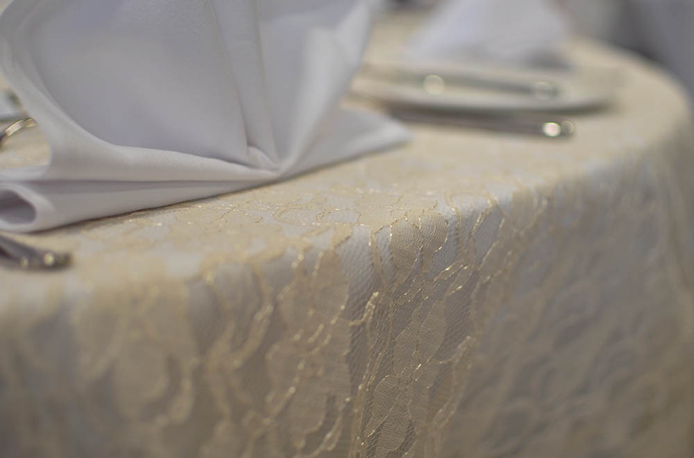Ivory table cloth overlay for a wedding table setup