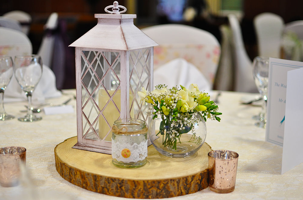 Rustic lantern and floral log slice table wedding centrepiece