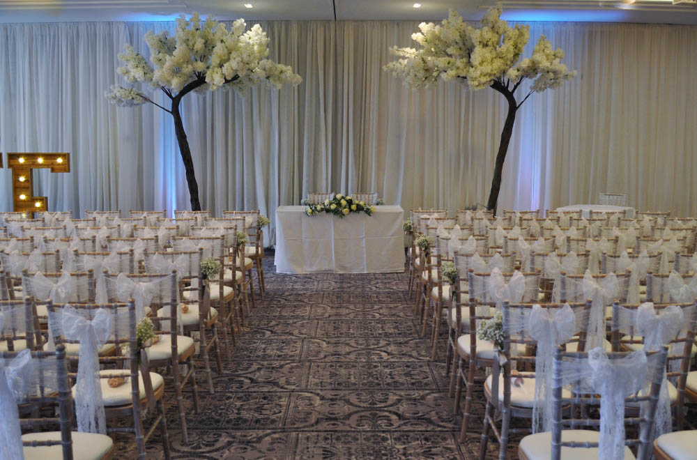 Wedding ceremony set up at De Vere Tortworth Court with drapes and large blossom trees