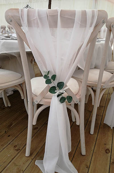White chiffon drops on rustic chairs, with eucalyptus detailing