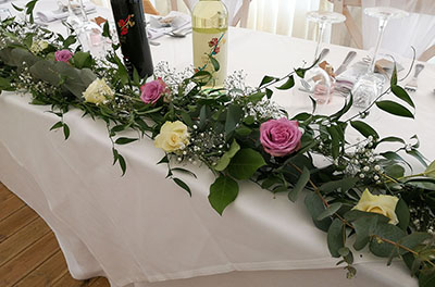 Full length, loose top table arrangement with foliage, roses, gypsophilla and floating candles