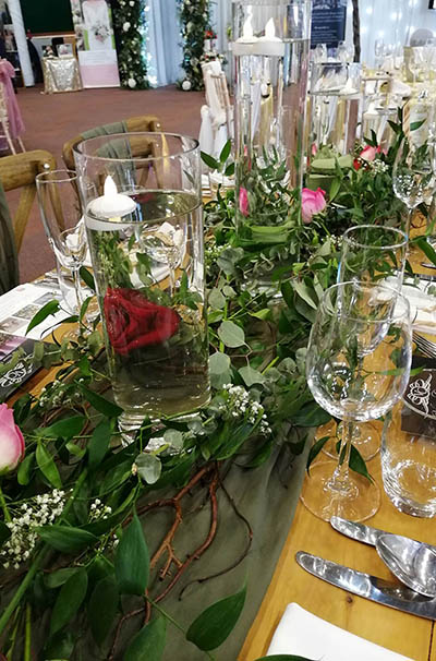 Full length loose foliage runner on top table, with roses and gypsophilla