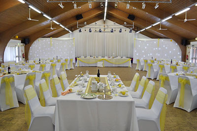 Yellow wedding at the Supermarines RFC, with chair covers and sashes, and full stage drape setup