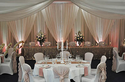 Warm Candlelit wedding with backdrop drapes behind the top table at the Cotswold Water Park Hotel