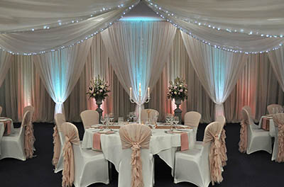 Wedding at the Cotswold Waterpark Hotel with warm room drapes and ruffle chair covers