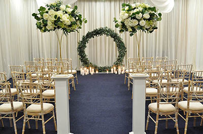 Wedding Ceremony with white floral columns with floral loop with candles