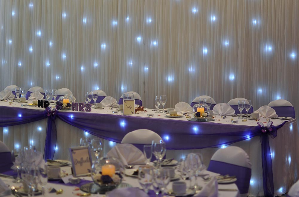 Top table Starlit table overlay and purple swag for a wedding.