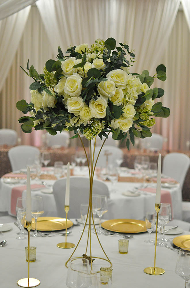Artificial flower floral wedding table centrepiece on gold wire stand with rose heads at De Vere Cotswold Water Park Hotel.