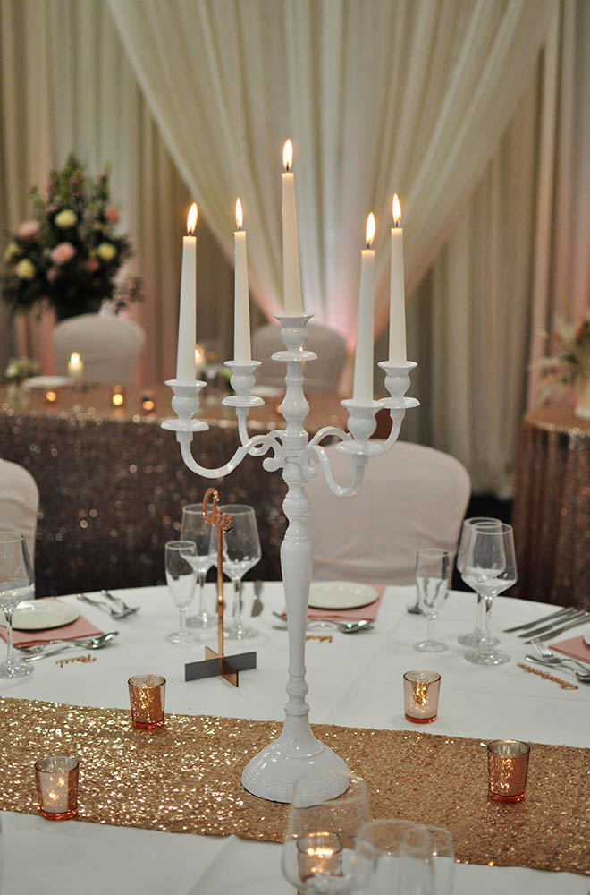 White wedding candelabra for a pink sequin wedding set up with lit candles