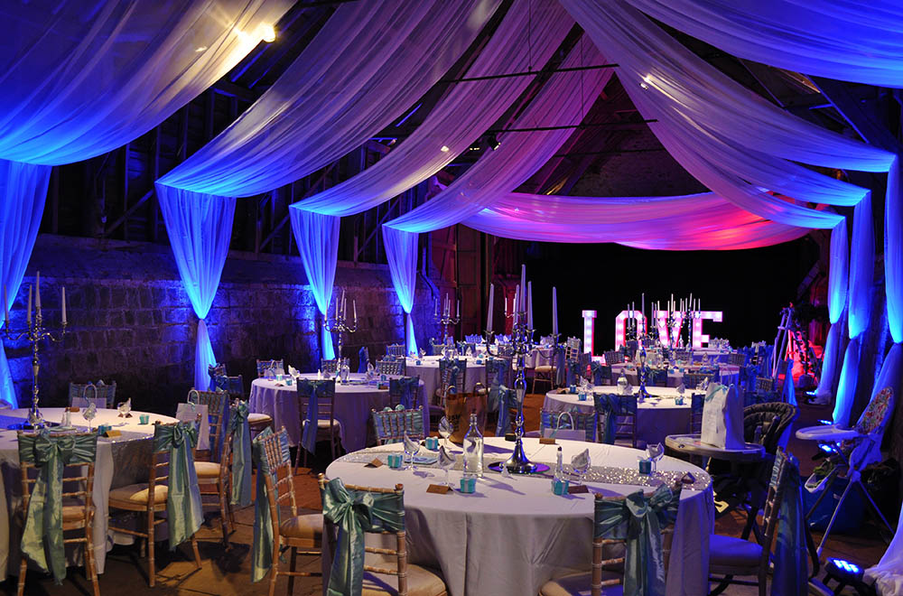 Ceiling and wall sail drapes at Wick Bottom barn wedding breakfast with Blue, pink and purple LED uplighting and chair sashes